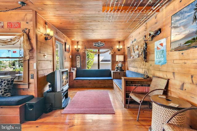 living area with hardwood / wood-style floors, wood ceiling, and wooden walls