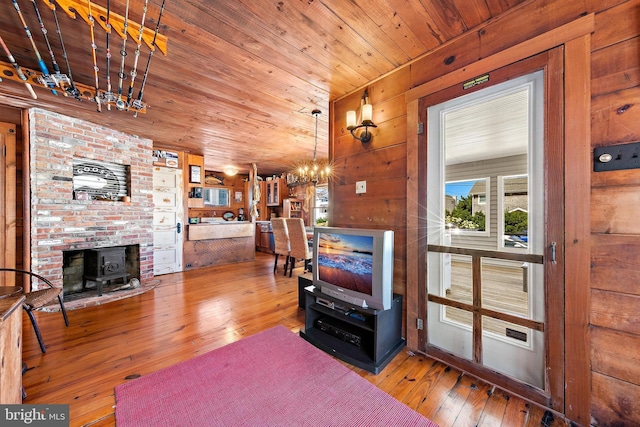 living room featuring hardwood / wood-style flooring, wooden ceiling, wood walls, and an inviting chandelier