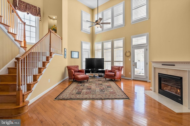 living room with ceiling fan, a premium fireplace, a healthy amount of sunlight, and light hardwood / wood-style flooring