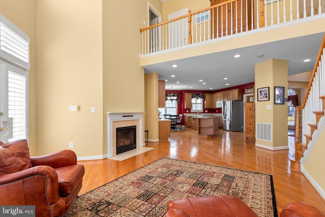 living room featuring a towering ceiling and light hardwood / wood-style floors