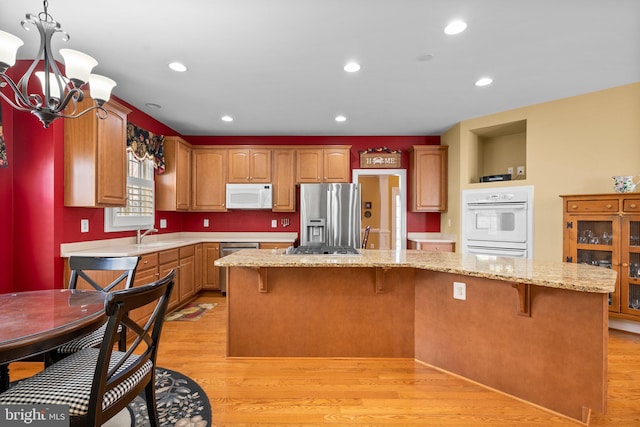 kitchen with a breakfast bar area, light wood-type flooring, stainless steel appliances, and a center island