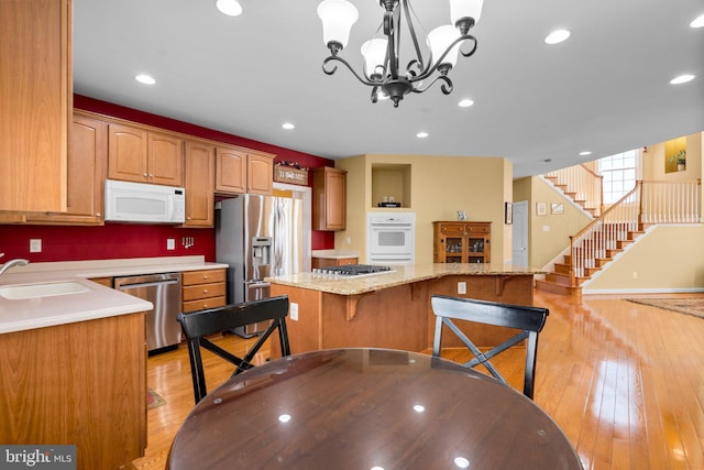 kitchen featuring a kitchen island, sink, stainless steel appliances, and hanging light fixtures