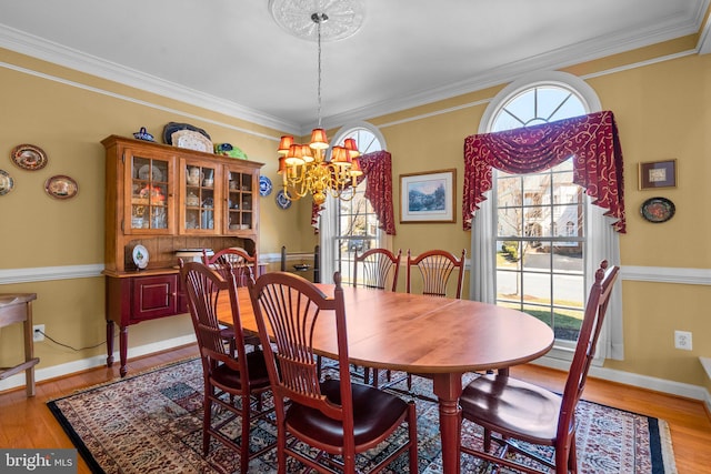 dining area with an inviting chandelier, crown molding, and light hardwood / wood-style flooring