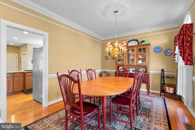 dining area with light hardwood / wood-style floors, a notable chandelier, and ornamental molding