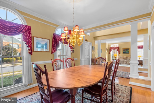 dining room with decorative columns, ornamental molding, and light hardwood / wood-style flooring