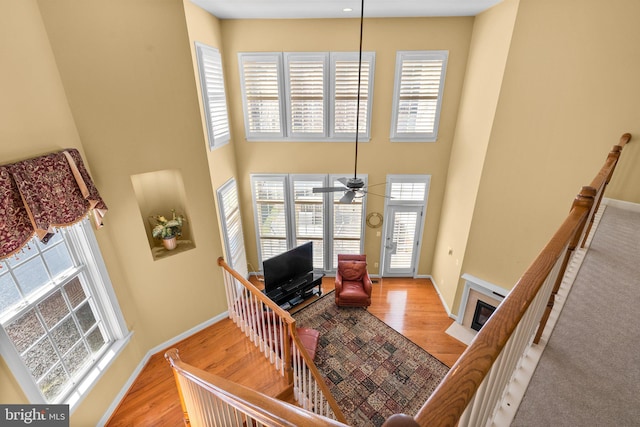 living room featuring ceiling fan, light hardwood / wood-style floors, and a high ceiling