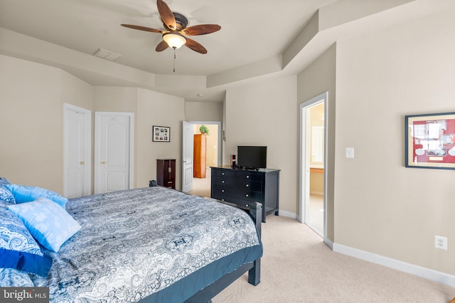 carpeted bedroom featuring a tray ceiling and ceiling fan