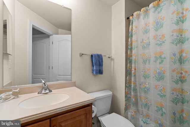 bathroom featuring curtained shower, vanity, and toilet