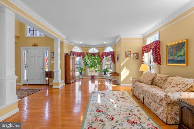 entryway featuring light wood-type flooring, crown molding, and decorative columns