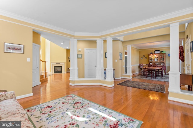 entryway with wood-type flooring, crown molding, and ornate columns