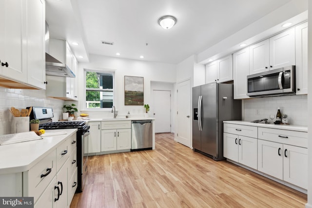 kitchen featuring sink, light wood-type flooring, white cabinets, stainless steel appliances, and backsplash