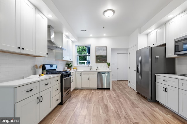 kitchen featuring white cabinetry, appliances with stainless steel finishes, and wall chimney exhaust hood