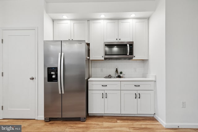 kitchen featuring backsplash, light hardwood / wood-style flooring, stainless steel appliances, and white cabinets