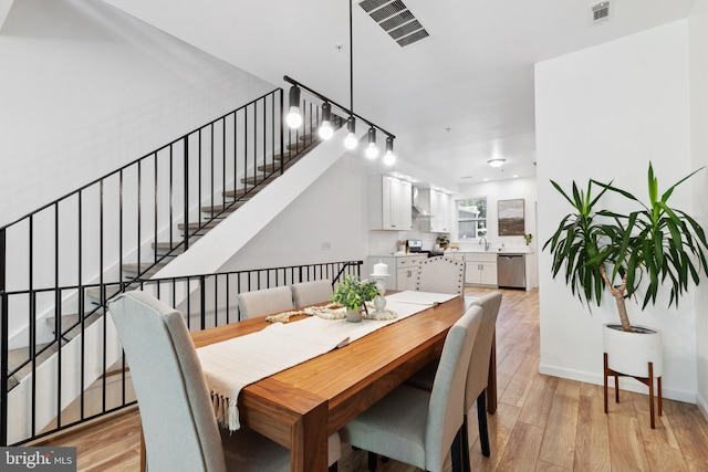 dining space with sink and light hardwood / wood-style flooring