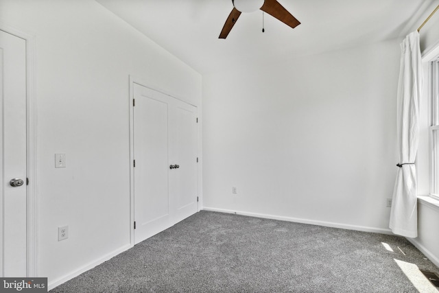 unfurnished bedroom featuring ceiling fan and dark carpet