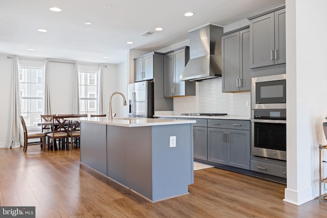 kitchen featuring appliances with stainless steel finishes, gray cabinets, and wall chimney exhaust hood