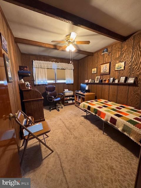 bedroom with carpet flooring, beam ceiling, and wood walls