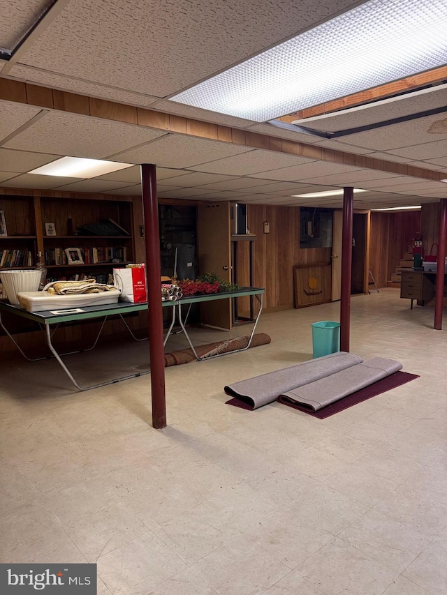 basement with a paneled ceiling and wooden walls