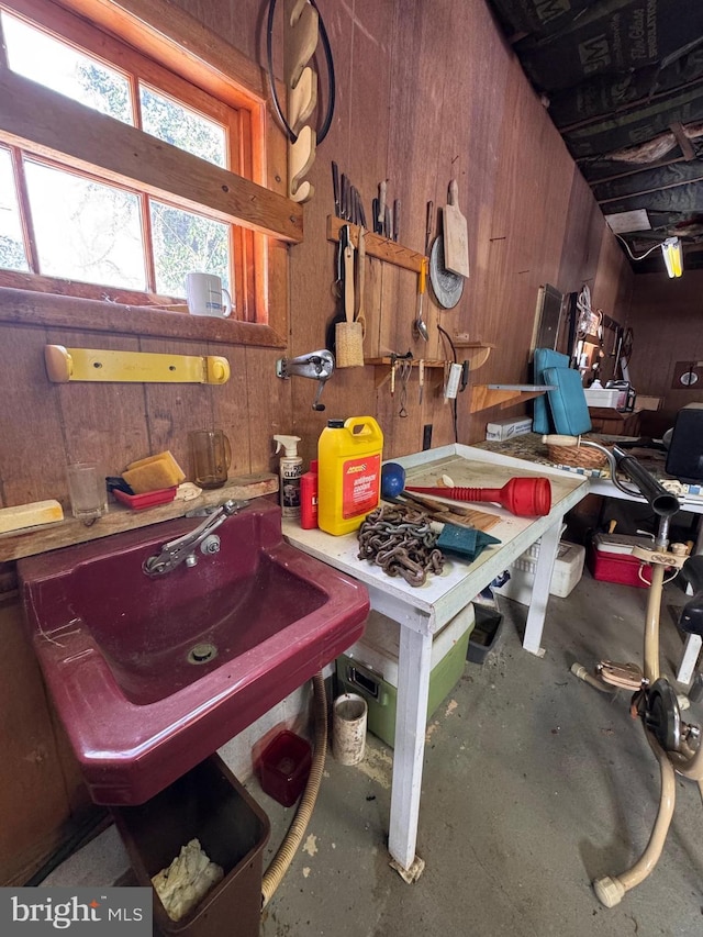 interior space featuring concrete flooring, sink, a workshop area, and wood walls