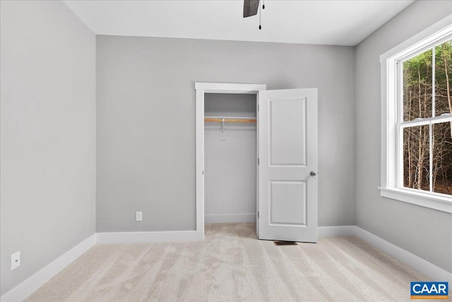 unfurnished bedroom featuring ceiling fan, a closet, and light colored carpet