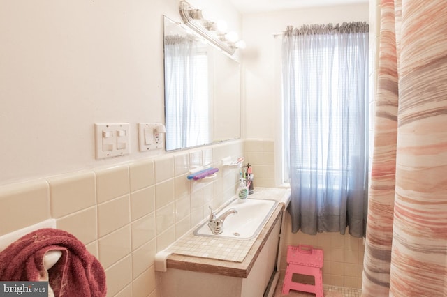 bathroom featuring vanity and tile walls