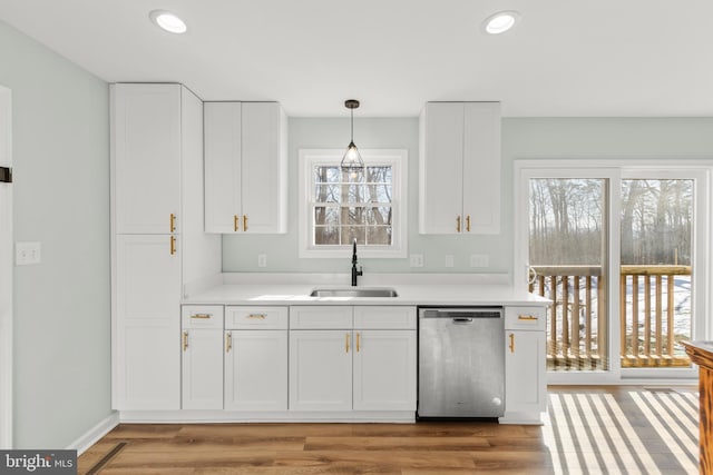 kitchen with white cabinetry, sink, decorative light fixtures, and stainless steel dishwasher