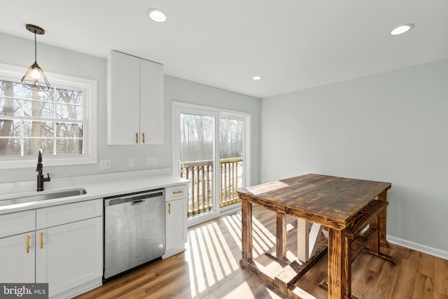 kitchen featuring dishwasher, sink, white cabinets, and decorative light fixtures