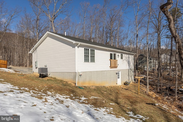 snow covered property featuring central AC unit