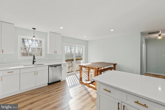 kitchen featuring sink, decorative light fixtures, light wood-type flooring, stainless steel dishwasher, and white cabinets