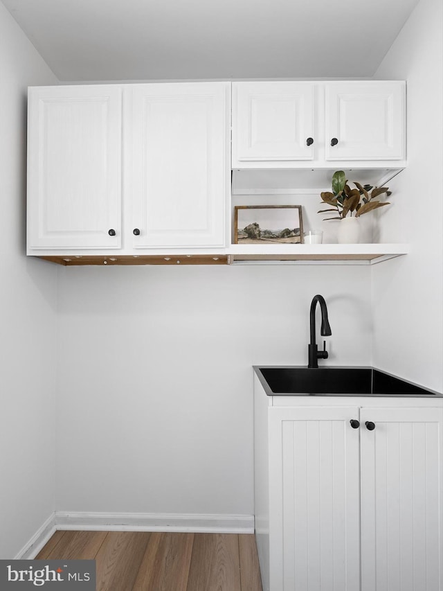 bar with sink, wood-type flooring, and white cabinets