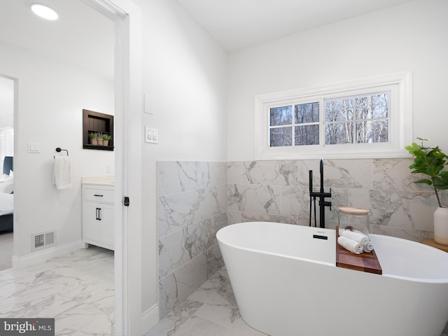 bathroom with a tub, tile walls, and vanity