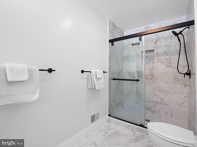 bathroom featuring toilet and a shower with door