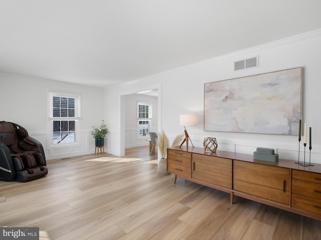 living area with light wood-type flooring and crown molding