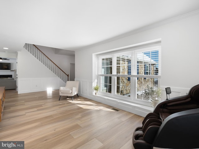 sitting room featuring ceiling fan, light wood-type flooring, and crown molding