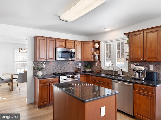 kitchen featuring light hardwood / wood-style floors, stainless steel appliances, dark stone counters, a kitchen island, and sink