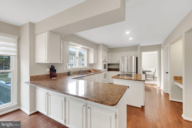 kitchen with sink, white cabinets, stainless steel refrigerator, and kitchen peninsula