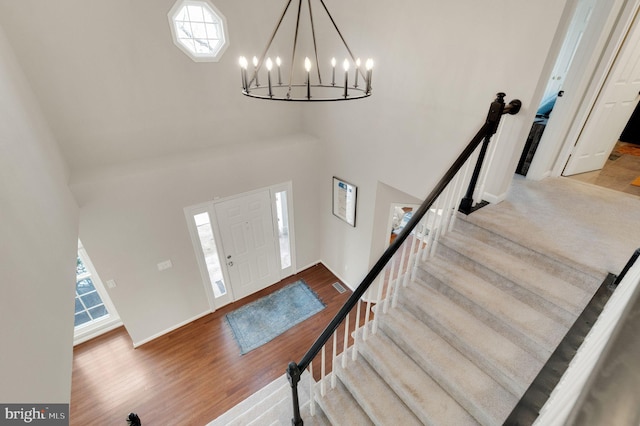 foyer entrance with hardwood / wood-style floors, a towering ceiling, and a chandelier