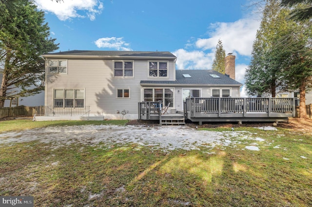 back of property featuring a wooden deck and a lawn