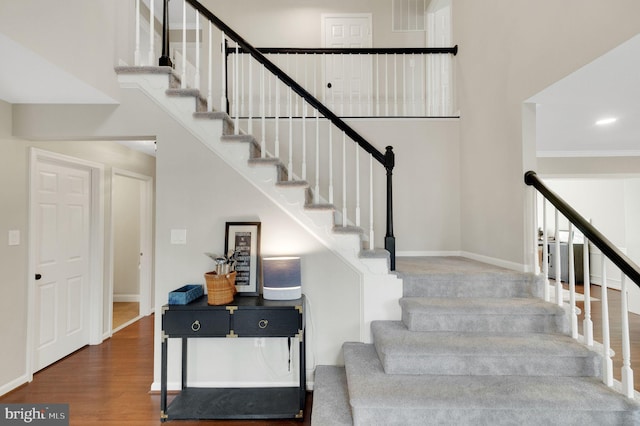 staircase featuring hardwood / wood-style flooring and a towering ceiling