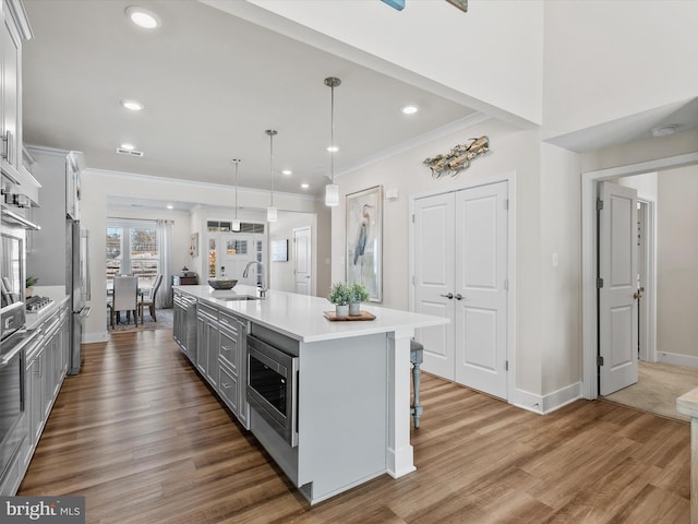 kitchen with decorative light fixtures, sink, a kitchen island with sink, a breakfast bar, and stainless steel appliances