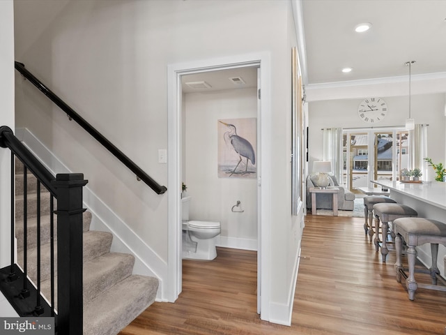 staircase featuring hardwood / wood-style flooring and ornamental molding