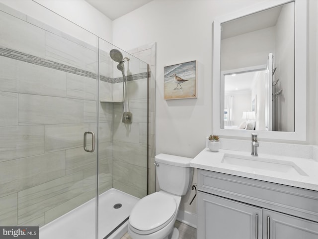 bathroom featuring toilet, an enclosed shower, and vanity