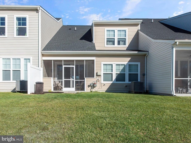 rear view of house with cooling unit, a sunroom, and a yard