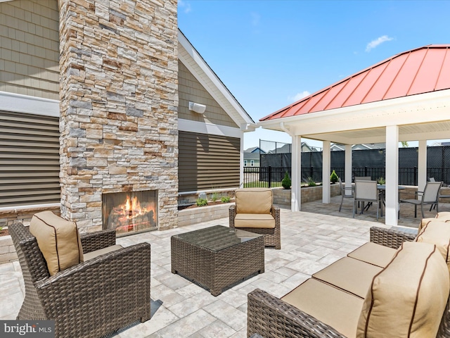 view of patio with a gazebo and an outdoor living space with a fireplace