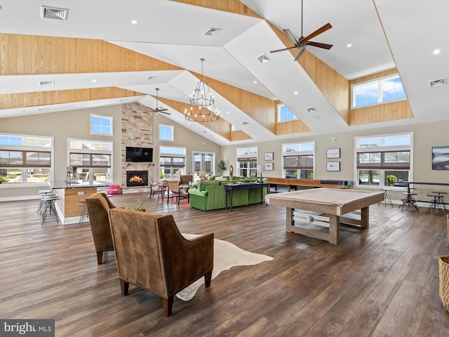 living room featuring a towering ceiling, pool table, a stone fireplace, dark hardwood / wood-style floors, and ceiling fan