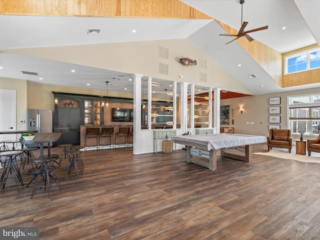 recreation room with indoor bar, ceiling fan, dark hardwood / wood-style flooring, a high ceiling, and decorative columns