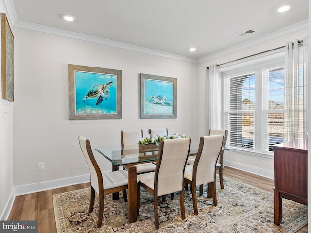 dining space featuring a wealth of natural light, ornamental molding, and wood-type flooring