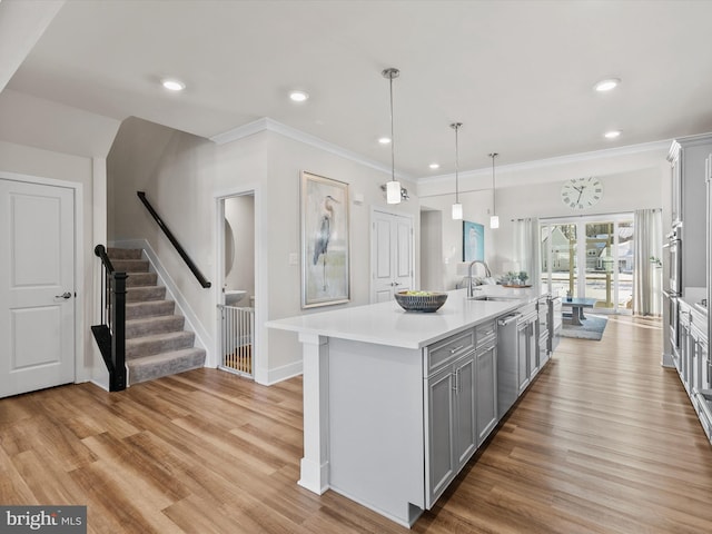 kitchen featuring pendant lighting, light hardwood / wood-style flooring, dishwasher, gray cabinetry, and an island with sink