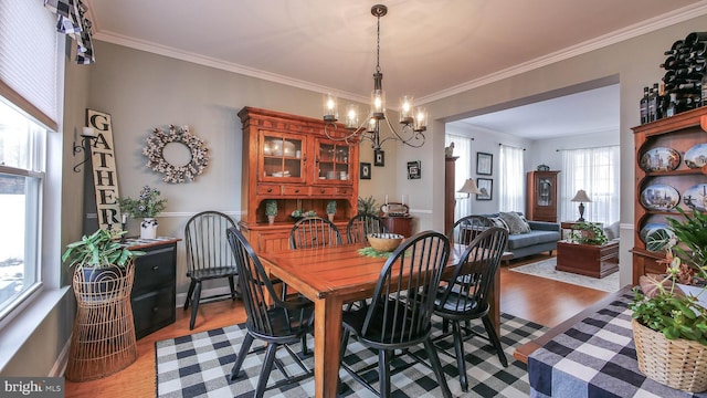 dining area featuring light hardwood / wood-style flooring, ornamental molding, and an inviting chandelier