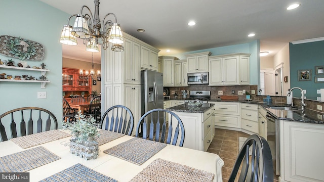 kitchen featuring appliances with stainless steel finishes, tasteful backsplash, a notable chandelier, pendant lighting, and sink